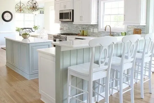 A kitchen with white cabinets and wooden floors.